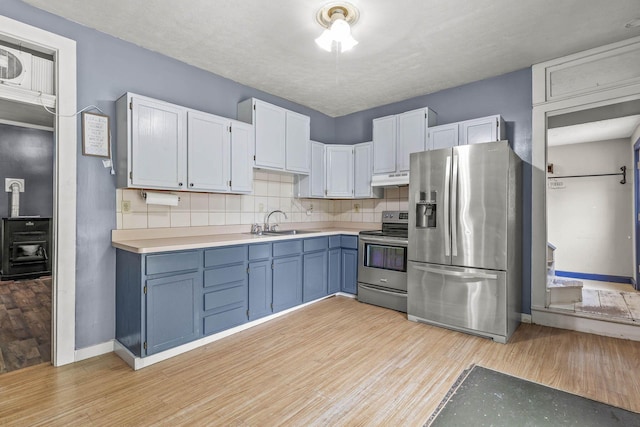 kitchen featuring backsplash, sink, light hardwood / wood-style floors, white cabinetry, and stainless steel appliances