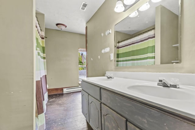 bathroom with hardwood / wood-style floors, vanity, and a baseboard heating unit