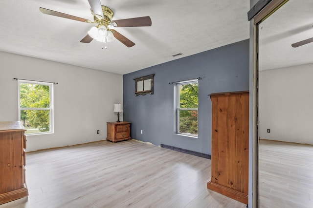 interior space featuring a wealth of natural light, ceiling fan, light hardwood / wood-style floors, and a textured ceiling