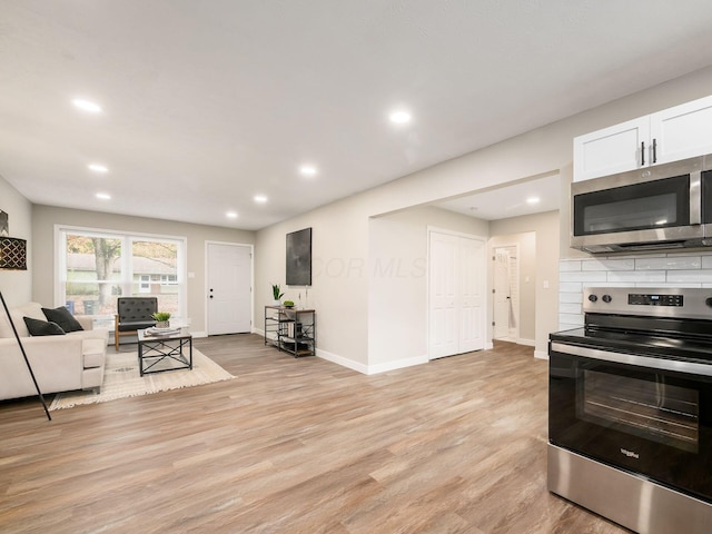 kitchen with light hardwood / wood-style flooring, white cabinets, and appliances with stainless steel finishes