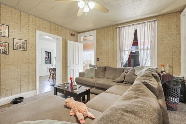 living area featuring baseboards, visible vents, a ceiling fan, and wallpapered walls