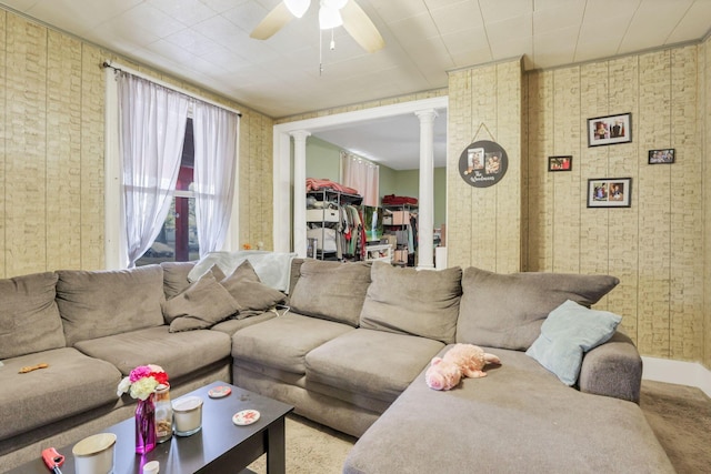 living room featuring ceiling fan, baseboards, decorative columns, and wallpapered walls