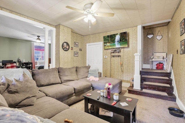 living room with wallpapered walls, a ceiling fan, light carpet, ornate columns, and stairs