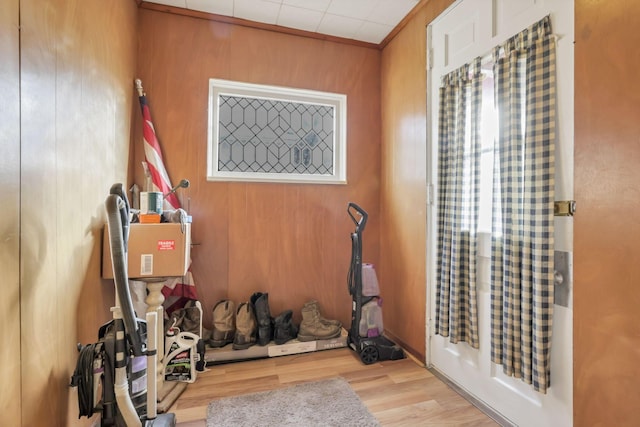 workout area with light wood-type flooring, crown molding, and wooden walls