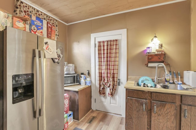 kitchen featuring stainless steel appliances, light countertops, light wood-style floors, ornamental molding, and a sink