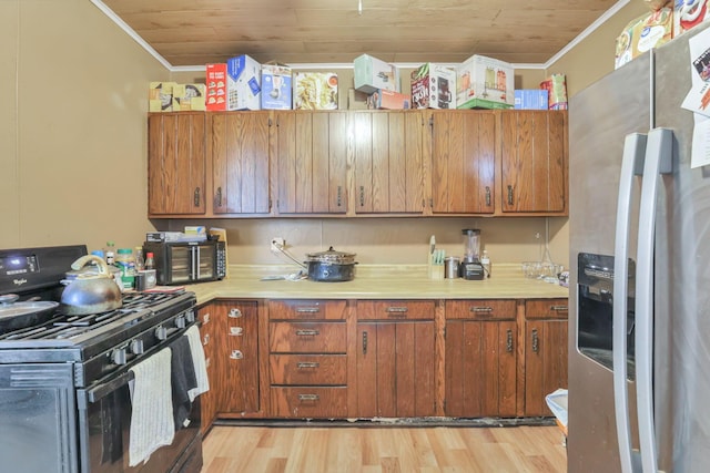 kitchen featuring light wood finished floors, ornamental molding, black range with gas stovetop, light countertops, and stainless steel refrigerator with ice dispenser