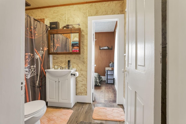 bathroom featuring toilet, wallpapered walls, wood finished floors, and vanity