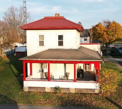 rear view of house featuring covered porch, metal roof, and a chimney