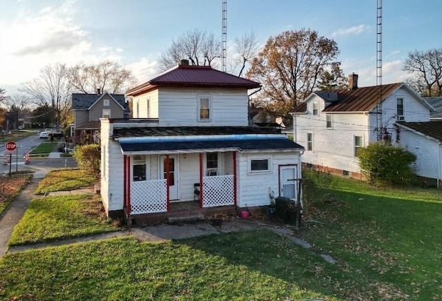 back of property featuring covered porch, a yard, metal roof, and a chimney