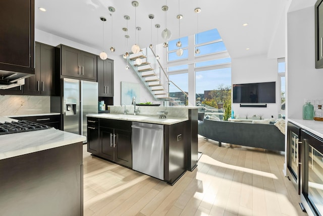 kitchen featuring backsplash, stainless steel appliances, sink, pendant lighting, and light hardwood / wood-style floors