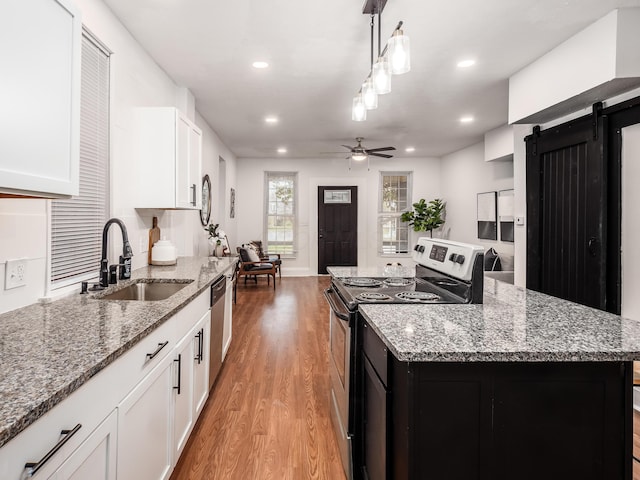 1327 Atcheson St, Columbus, OH 43203 - kitchen featuring electric stove, light wood-style floors, a barn door, a center island, and white cabinetry
