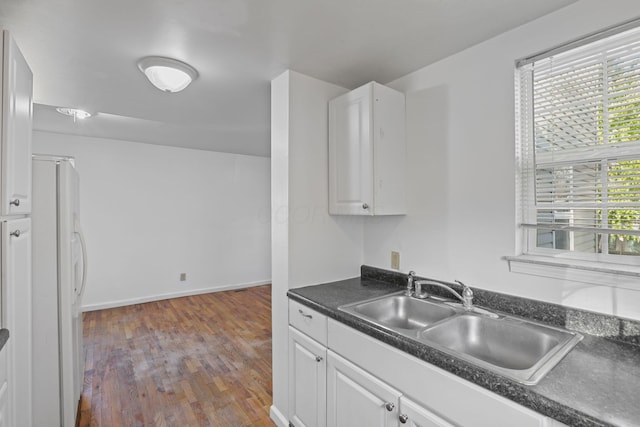 kitchen with white cabinetry, sink, wood-type flooring, and white refrigerator