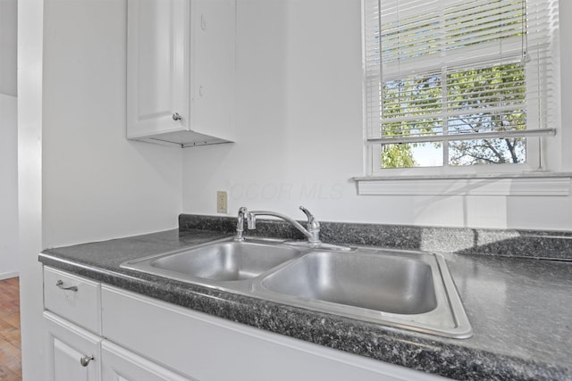 kitchen with hardwood / wood-style floors, white cabinets, and sink