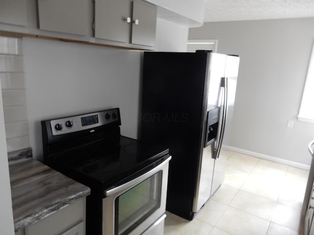 kitchen featuring gray cabinetry, light tile patterned flooring, a textured ceiling, and appliances with stainless steel finishes