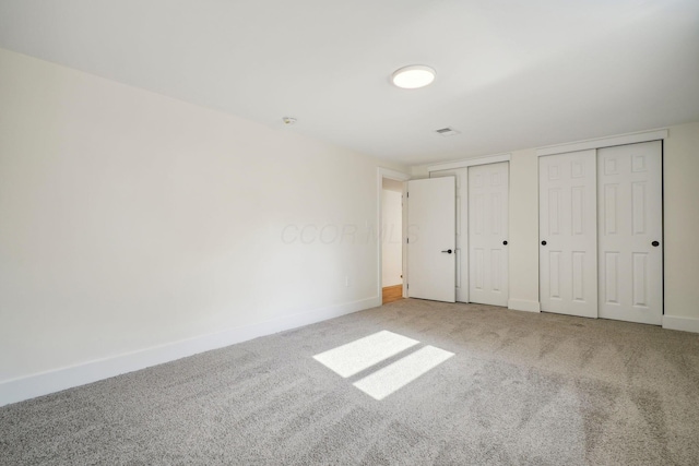 unfurnished bedroom with carpet flooring and multiple closets