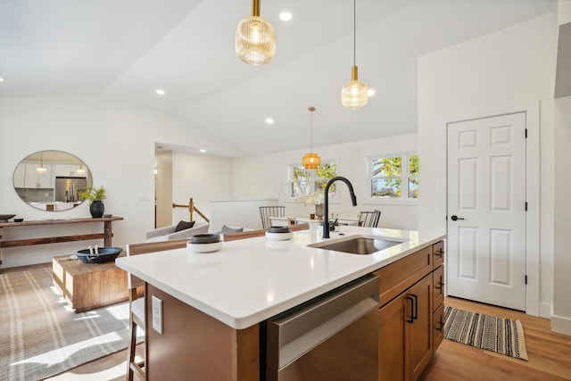 kitchen with sink, vaulted ceiling, light wood-type flooring, an island with sink, and stainless steel appliances