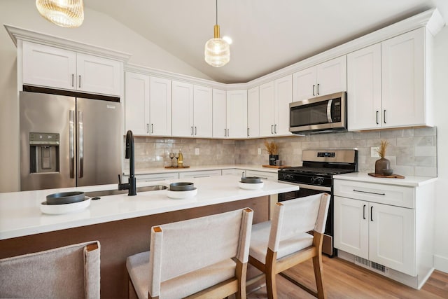 kitchen with white cabinets, appliances with stainless steel finishes, and decorative light fixtures