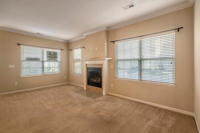 unfurnished living room with a tiled fireplace, light colored carpet, and ornamental molding