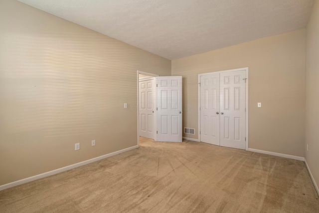 unfurnished bedroom featuring a closet and light colored carpet