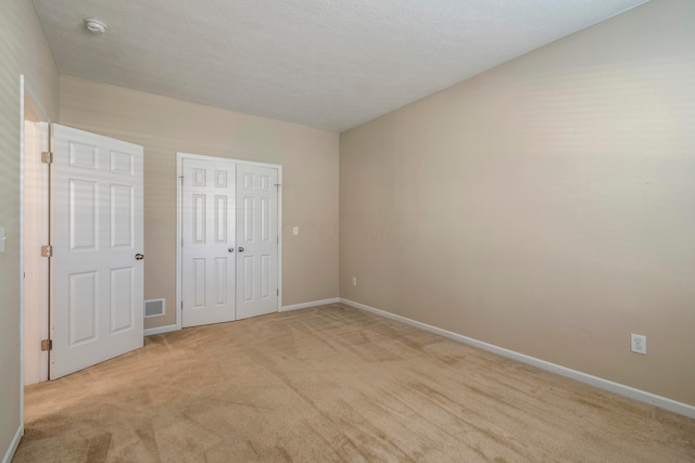 unfurnished bedroom with light carpet, a closet, and a textured ceiling