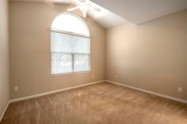 empty room featuring ceiling fan, light colored carpet, and vaulted ceiling