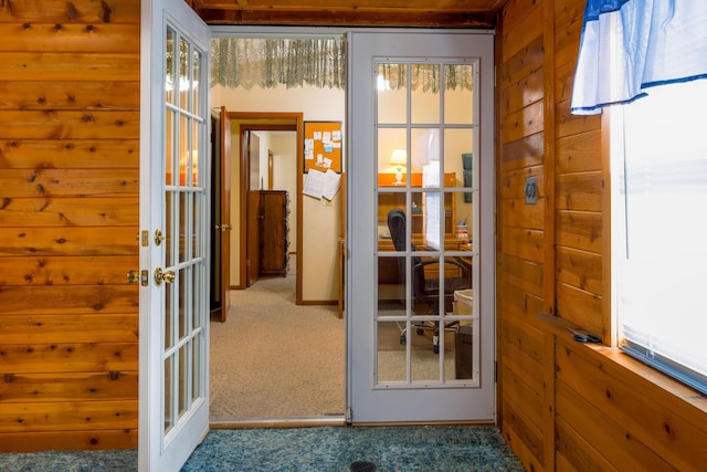 doorway to outside featuring french doors, carpet floors, and wood walls