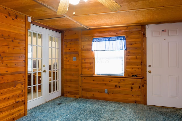 carpeted spare room with wood ceiling, a healthy amount of sunlight, and wood walls