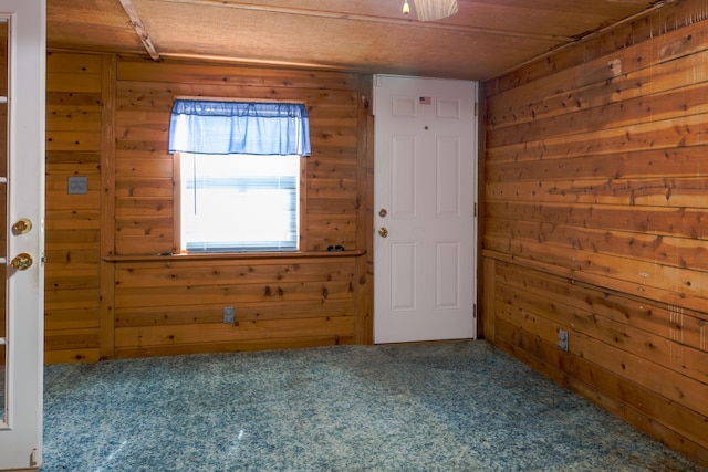 spare room featuring carpet flooring and wood walls