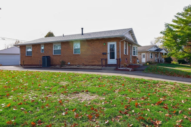 view of front of home featuring central air condition unit, a front lawn, an outdoor structure, and a garage