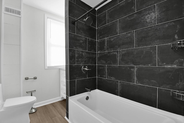 bathroom featuring toilet, hardwood / wood-style floors, and tiled shower / bath