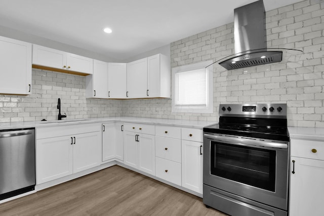 kitchen featuring white cabinets, sink, wall chimney exhaust hood, and appliances with stainless steel finishes