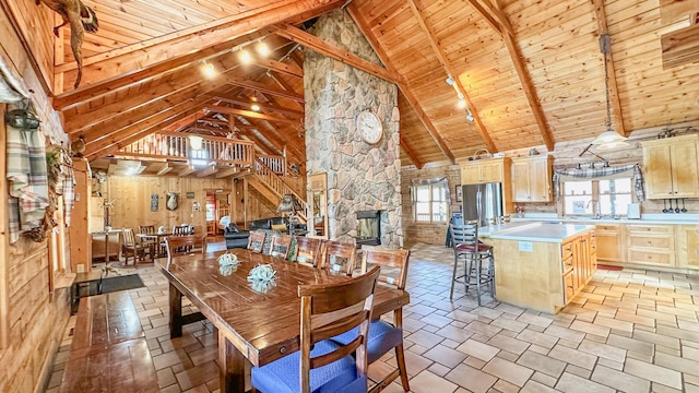 dining area featuring wood ceiling, sink, beam ceiling, high vaulted ceiling, and wood walls