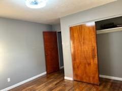 unfurnished bedroom with a closet and dark wood-type flooring