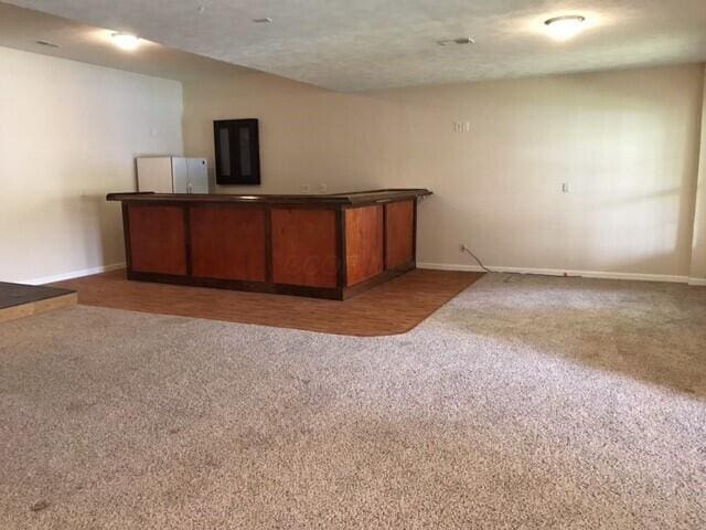 bar with a textured ceiling and dark colored carpet