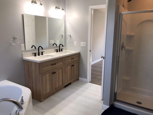 bathroom with hardwood / wood-style floors, vanity, and shower with separate bathtub