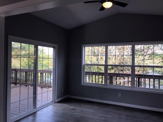 empty room with vaulted ceiling, ceiling fan, and dark wood-type flooring