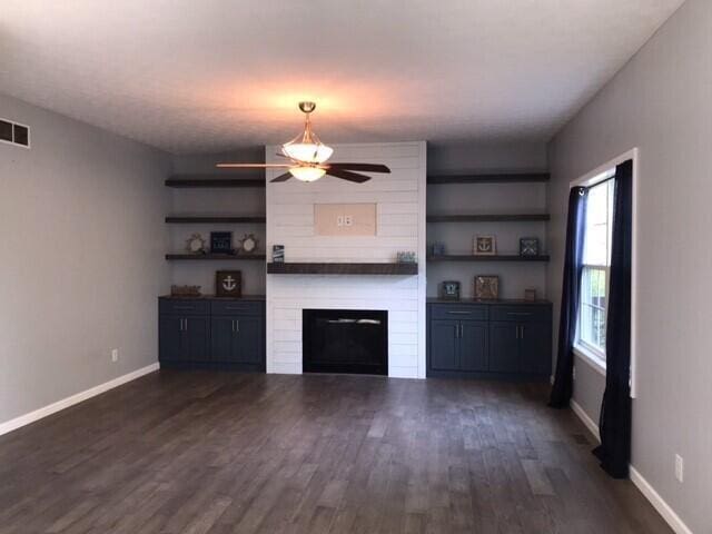 unfurnished living room featuring dark hardwood / wood-style flooring, ceiling fan, and a fireplace