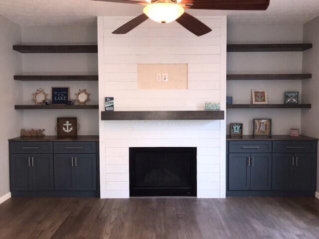 unfurnished living room with a large fireplace, dark hardwood / wood-style flooring, built in features, and a textured ceiling