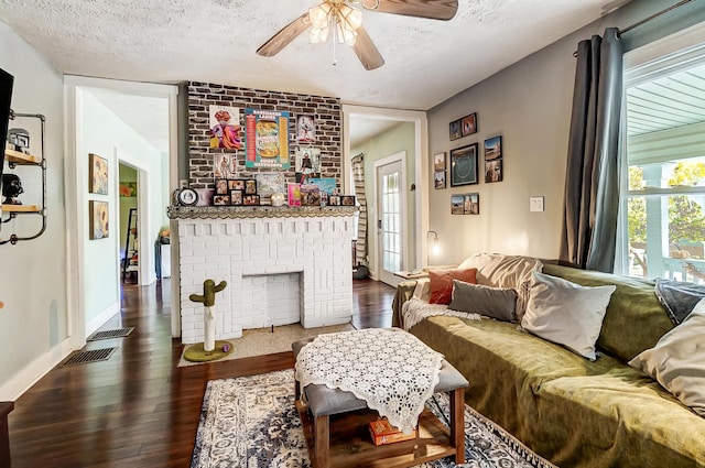 living room featuring a fireplace, a textured ceiling, ceiling fan, and dark wood-type flooring