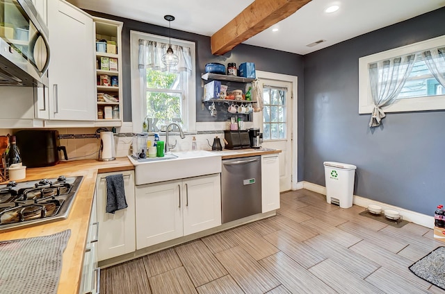 kitchen featuring butcher block counters, white cabinetry, hanging light fixtures, and stainless steel appliances