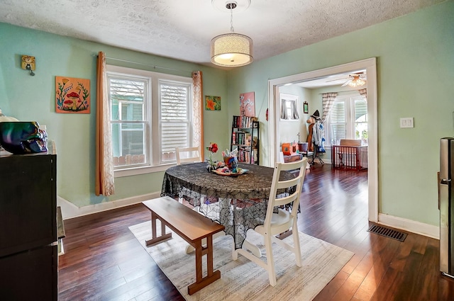 dining space with a textured ceiling, plenty of natural light, and dark wood-type flooring