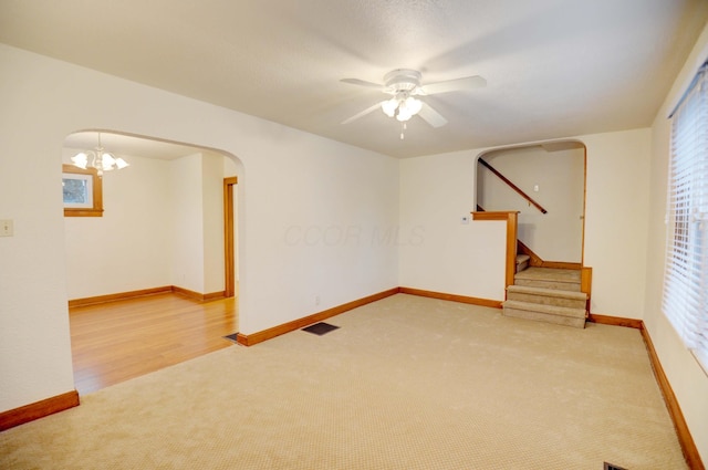 empty room with light hardwood / wood-style flooring and ceiling fan with notable chandelier