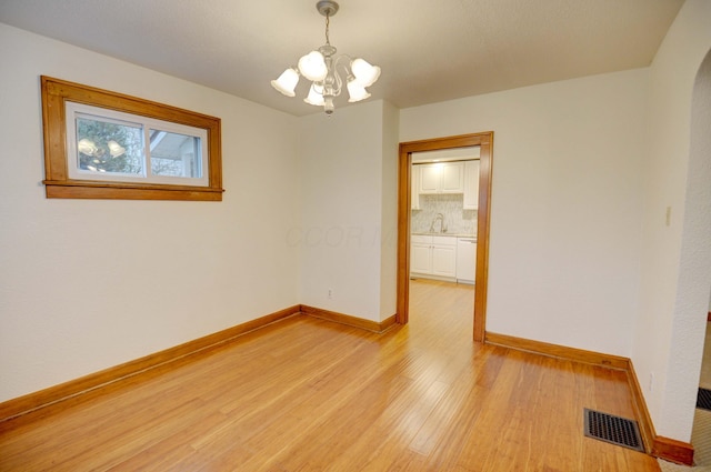 spare room with light hardwood / wood-style floors, a notable chandelier, and sink