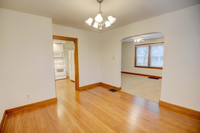 unfurnished room with ceiling fan with notable chandelier and hardwood / wood-style flooring