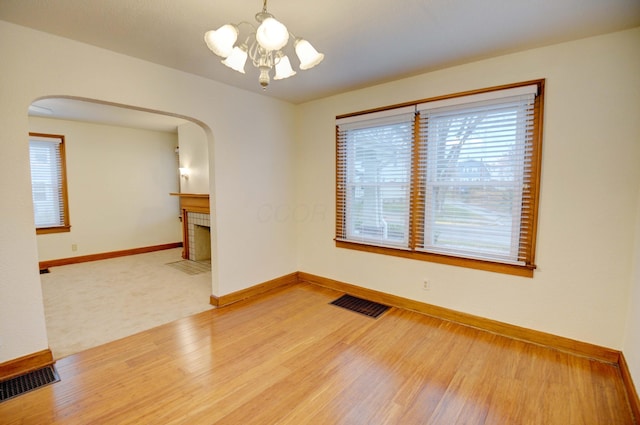 unfurnished room featuring a chandelier, hardwood / wood-style floors, and a tile fireplace