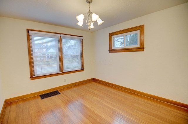 unfurnished room with hardwood / wood-style floors and a chandelier