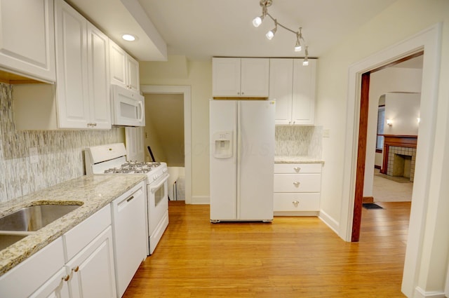 kitchen with light stone countertops, white appliances, light hardwood / wood-style floors, and white cabinetry