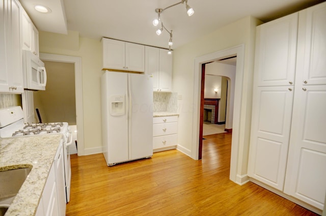 kitchen featuring light stone countertops, backsplash, light hardwood / wood-style floors, white appliances, and white cabinets