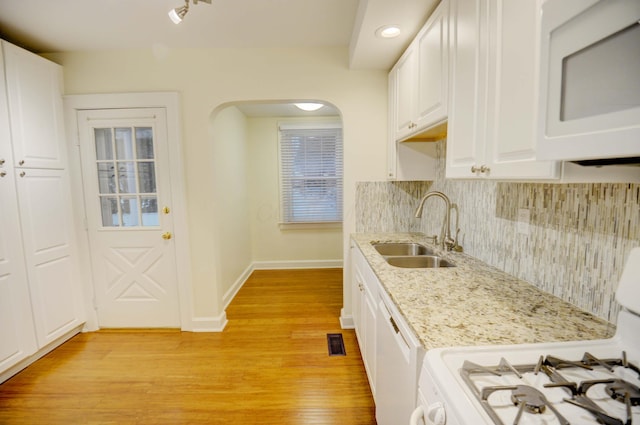 kitchen featuring sink, light stone counters, white appliances, white cabinets, and light wood-type flooring