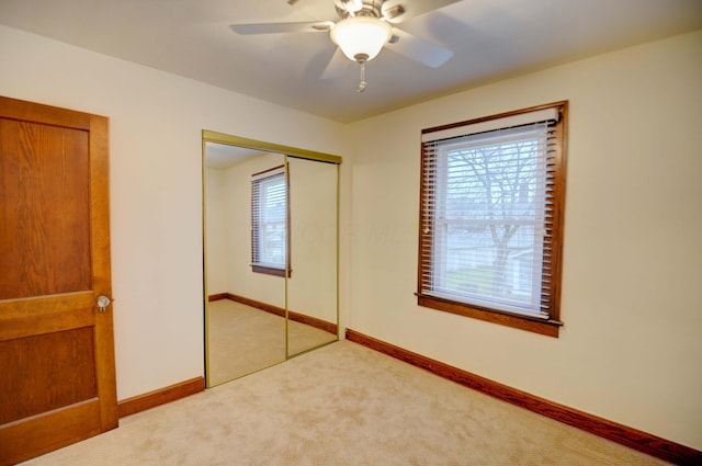 unfurnished bedroom featuring ceiling fan, light colored carpet, and a closet